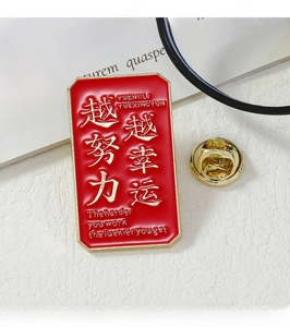Detail of red enamel badge with gold trim and lucky slogan on a white textured desk