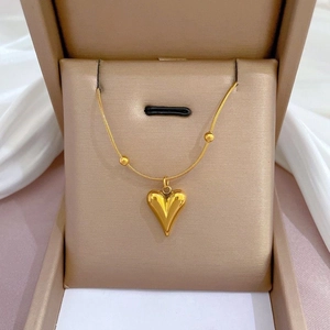 Close-up of a gold heart pendant necklace displayed elegantly in a beige jewelry box