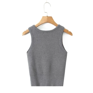 Close-up of a grey cropped knit vest with ribbed texture on a wooden hanger