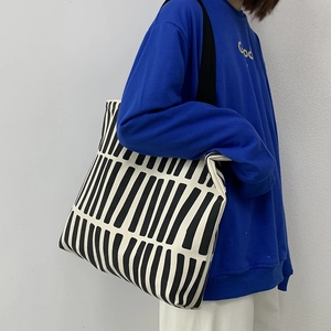 Black and white vertical striped canvas tote bag styled with a blue sweatshirt
