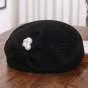 Detail of elegant black wool beret featuring mesh veil, bow and pearl accents