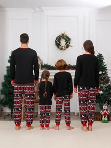 Family of four from behind wearing matching Christmas pajamas in a cozy festive room