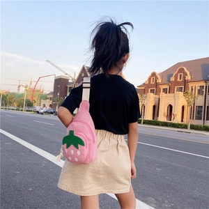 Pink strawberry canvas crossbody bag for girls showing the back view outdoors