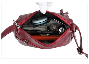 Detailed interior of a deep red faux leather crossbody bag with multiple compartments
