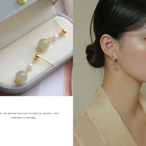 Close-up detail of vintage freshwater pearl drop earrings with light green beads and gold finish