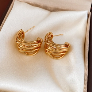 Close-up of gold plated C-shaped multi-layer twisted earrings in white satin jewelry box