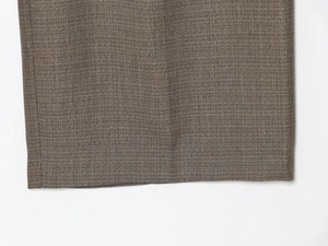 Detailed close-up of premium dark grey woven fabric hem for structured suit trousers