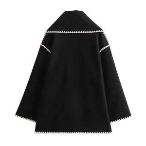 Detail of black wool coat featuring white zigzag fringe trim on the back and sleeves