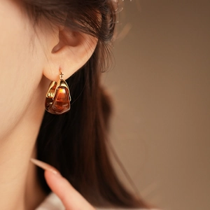 Macro shot of gold-plated hoop earrings with translucent amber resin pendants