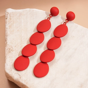 Exaggerated red matte geometric oval earrings with gold metal links on marble base