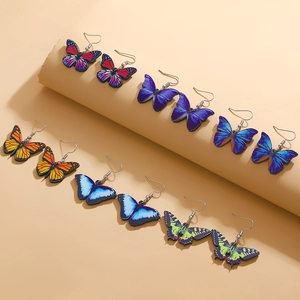 Detail view of colorful acrylic butterfly earrings set with vibrant patterned wings