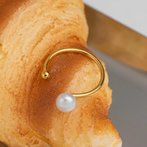 Dettaglio di un anello aperto placcato oro 18K con perla bianca e sfera d'oro su croissant