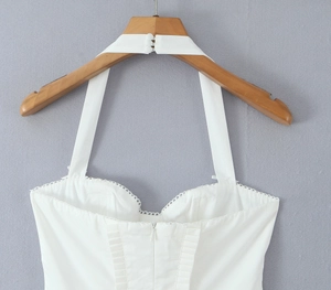 Close-up of white halter neck dress with back zipper and delicate lace edge details