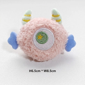 Detail of pink plush monster charm with blue wings and dimensions 6.5cm x 8.5cm