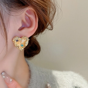Detail of heart stud earring with lava texture and colorful zircons on a model