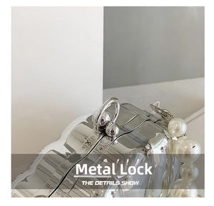Detail showing wave-textured silver shell bag with metallic ball clasp and pearl handle
