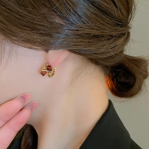 Close-up of gold twisted rope earrings featuring amber square-cut zircon crystals on earlobe