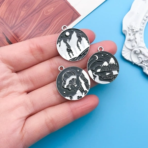 Close-up of three black and white mountain pendants shown in palm with hot air balloon motif