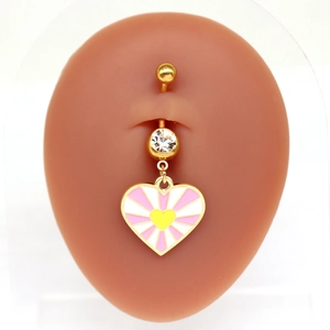 Détail d'un piercing de nombril doré avec pendentif coeur rose porté sur un modèle