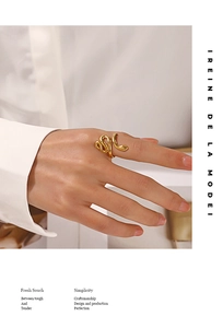 Détail d'une bague serpent dorée polie portée par un mannequin dans un style épuré