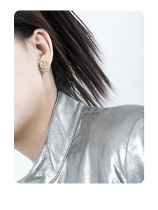 Close-up of two-tone gold and silver round stud earrings worn by a female model