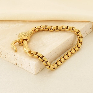 Detail of gold snake head clasp on square link chain bracelet with a luxury finish