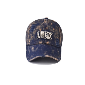 Detailed view of the vintage washed denim cap with distressed texture and LUCK embroidery
