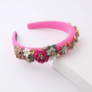 Elegant pink padded headband with floral accents, pearls, and crystals on a white block