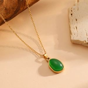 Dettaglio di una collana placcata oro con pendente ovale in pietra occhio di gatto verde