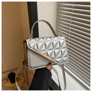 Detail of silver quilted texture handbag with gold metal bar and adjustable strap