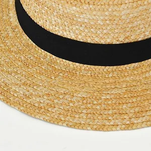 Close-up of woven straw texture and black grosgrain ribbon on the boater hat