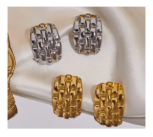 Dettaglio di orecchini a rombo vintage in oro e argento su seta bianca