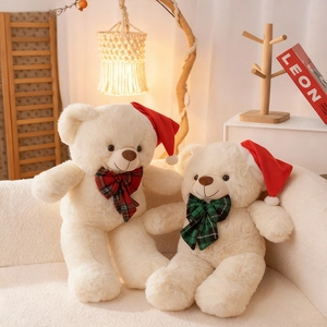 Plüschige Weihnachtsteddybären mit roten Mützen und karierten Schleifen auf weißem Sofa