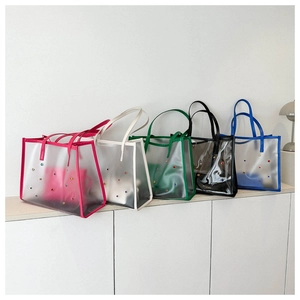 Row of colorful transparent PVC tote bags with rhinestone studs on a white display