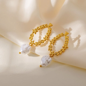 Detail of gold wreath earrings featuring white baroque pearls on a cream silk background