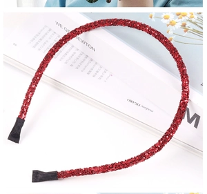 Detailed view of red rhinestone headband with sparkling gems and black protective tips