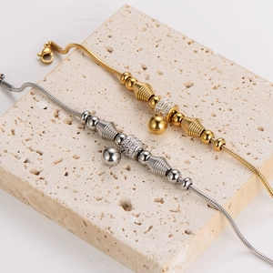 Minimalist gold and silver beaded snake chain bracelets on textured stone display tray