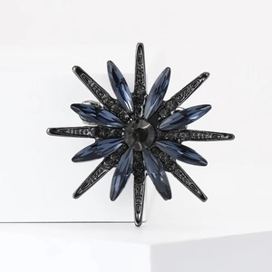 Detail of sunflower brooch with dark blue crystals and black gems on dark metal