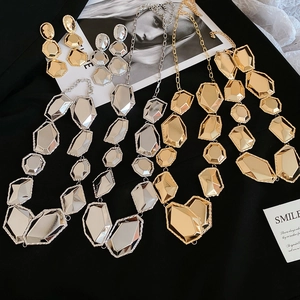 Vue détaillée du parure de bijoux géométriques en métal avec facettes sur fond noir