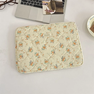 Close-up of quilted floral laptop sleeve with orange flowers and Sorakka label