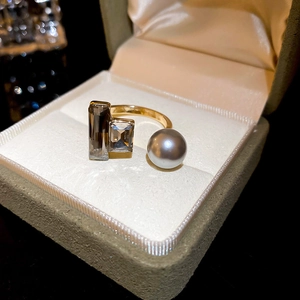 Detail of layered gold ring with grey pearl and rectangular crystals in a velvet box