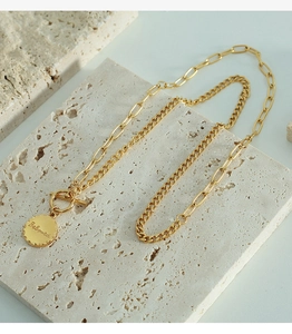 Macro shot of gold OT buckle necklace with double chains and engraved Beloved pendant
