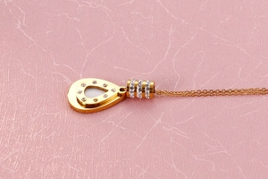 Detail of gold teardrop pendant necklace set with pavé rhinestones on leather background