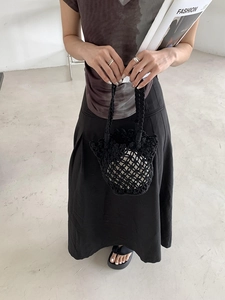 Detail of a black woven bucket bag showing the intricate knit pattern and soft texture