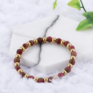Minimalist gold titanium steel beaded bracelet with faux garnet stones on marble
