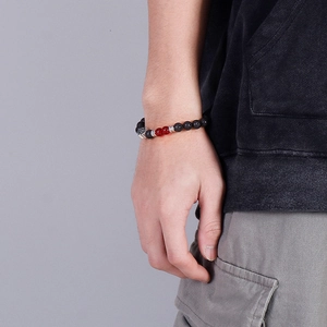 Detailed shot of lava stone bead bracelet with cross pendant on male model wrist