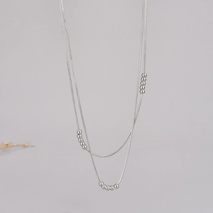 Detail of a silver double-layered snake chain necklace with small metal beads