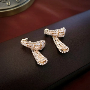 Detail of elegant gold ribbon earrings with inlaid baguette and round cut crystals