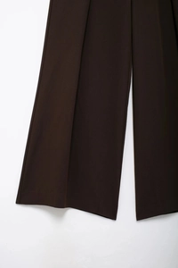Détail du pantalon large marron foncé en mélange de costume avec un drapé élégant