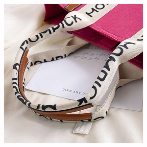 Detail of pink felt tote bag featuring MUMPICK webbing strap and leather reinforcement